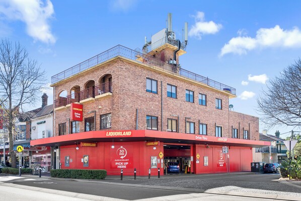 A red-brick building with a flat roof and a balcony on the second floor.