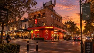 A street view at dusk with a prominent Liquorland bar and adjacent Greek food and coffee shop.