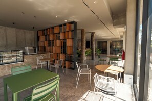 Een modern interieur met een zithoek, een houten boekenkast en een grote boomstam.