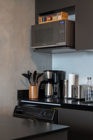 Eine Küche mit Mikrowelle, Kaffeemaschine, Toaster und einem Holz-Utensilienhalter.