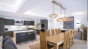 A modern kitchen with a central island, bar stools, and pendant lighting.