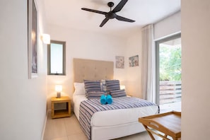 A bedroom with a bed, a nightstand, a ceiling fan, a window, and a view of greenery outside.