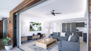 A modern living room with a grey sofa, wooden coffee table, and a flat-screen TV mounted on the wall.