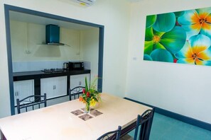 A dining area with a table, chairs, a vase with flowers, a microwave, and cabinets in the background. - 4-bedroom bungalow in tranquil setting (Tambon Choeng Thale)