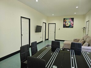 A conference room with a black table, four chairs, a sofa, and a wall-mounted TV. - 4-bedroom bungalow in tranquil setting (Tambon Choeng Thale)