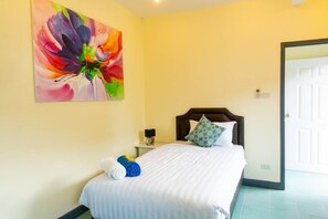 A hotel room with a bed, a painting, a nightstand, and a door. - 4-bedroom bungalow in tranquil setting (Tambon Choeng Thale)