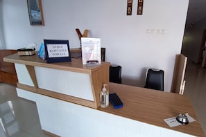 A reception desk with a sign indicating a waiting area, a tissue box, a water bottle, a phone, and a small bell.
