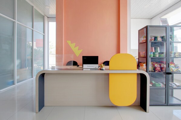 A reception desk with a computer, a small figurine, and a glass display case with snacks.