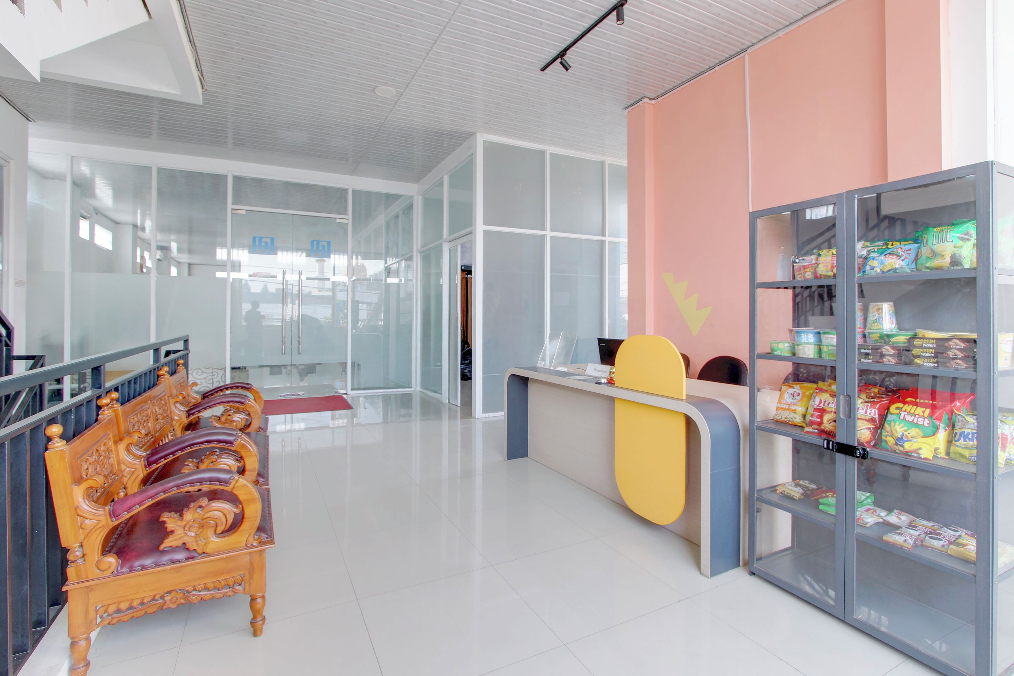 A modern interior with a reception desk, a snack vending machine, and a seating area with ornate chairs.