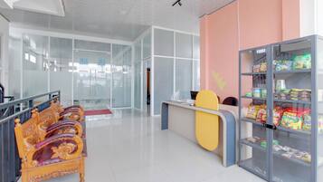 Un interior moderno con una mesa de recepción, una máquina expendedora de snacks y un área de descanso con sillas ornamentadas.
