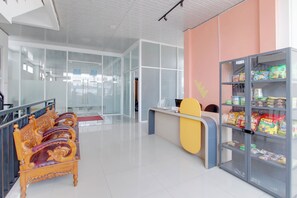 A modern interior with a reception desk, a snack vending machine, and a seating area with ornate chairs. - Collection O near Adisutjipto Airport (Depok)