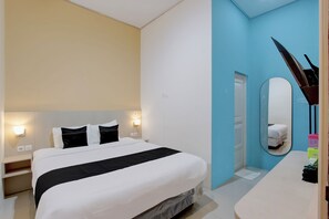 Une chambre d’hôtel avec un lit, des tables de chevet, un miroir et une porte de salle de bain.