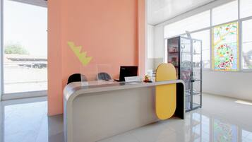Un mostrador de recepción con computadora, un separador de vidrio y una ventana con diseño de vitral.