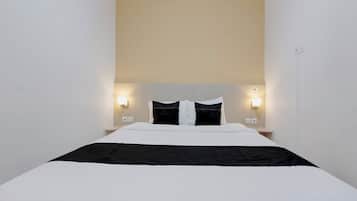 Una habitación de hotel con una cama, dos mesitas de noche y luces fijadas a la pared.