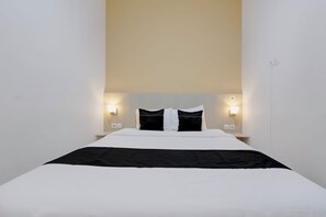 A hotel room with a bed, two bedside tables, and wall-mounted lights. - Collection O near Adisutjipto Airport (Depok)
