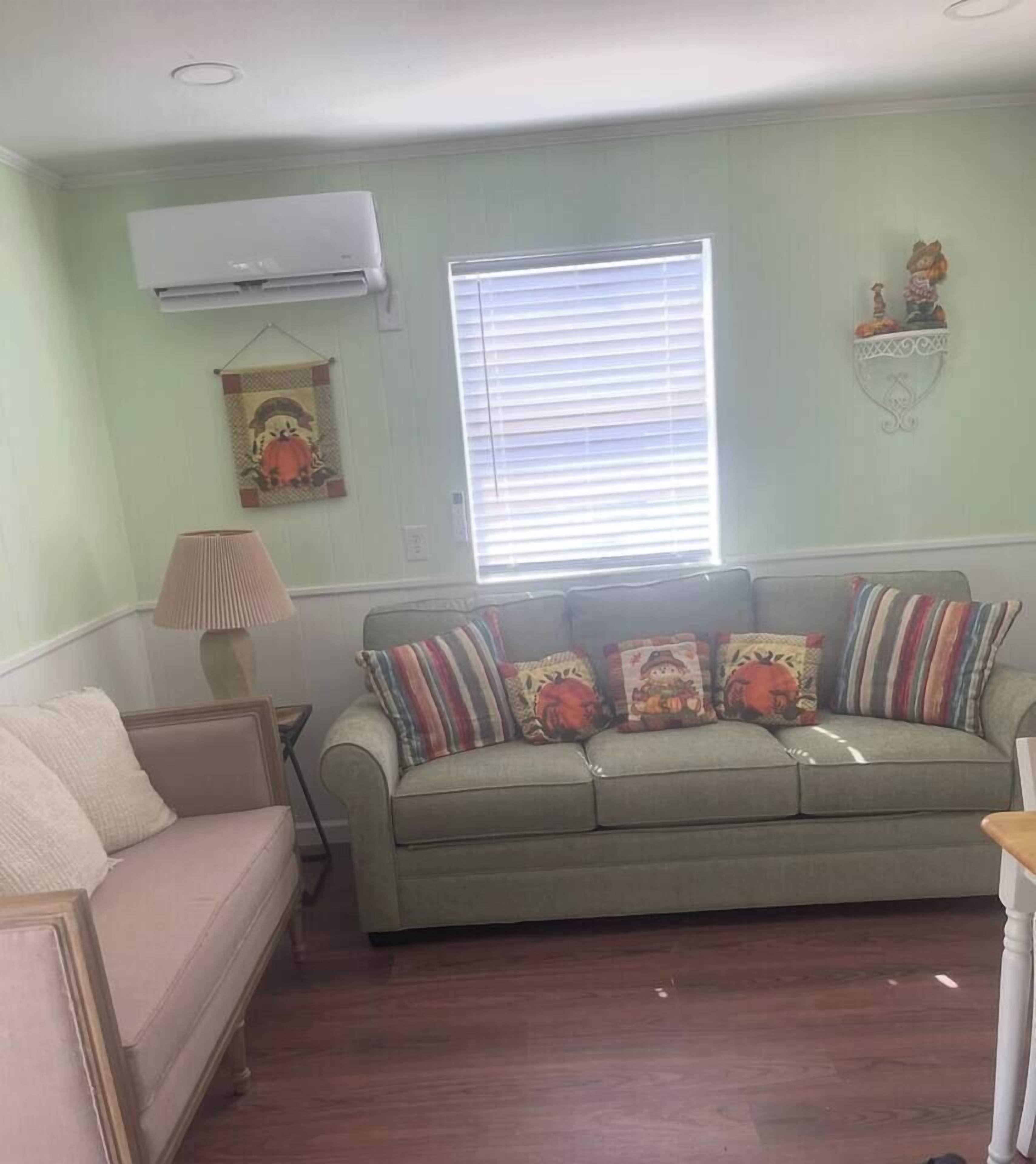 En stue med en grøn sofa, en beige sofa og en lampe.