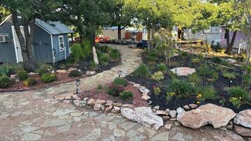 A garden pathway with a mix of stone and gravel, surrounded by various plants and shrubs.
