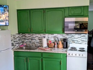 A kitchen with green cabinets, a white stove, and a tiled backsplash.