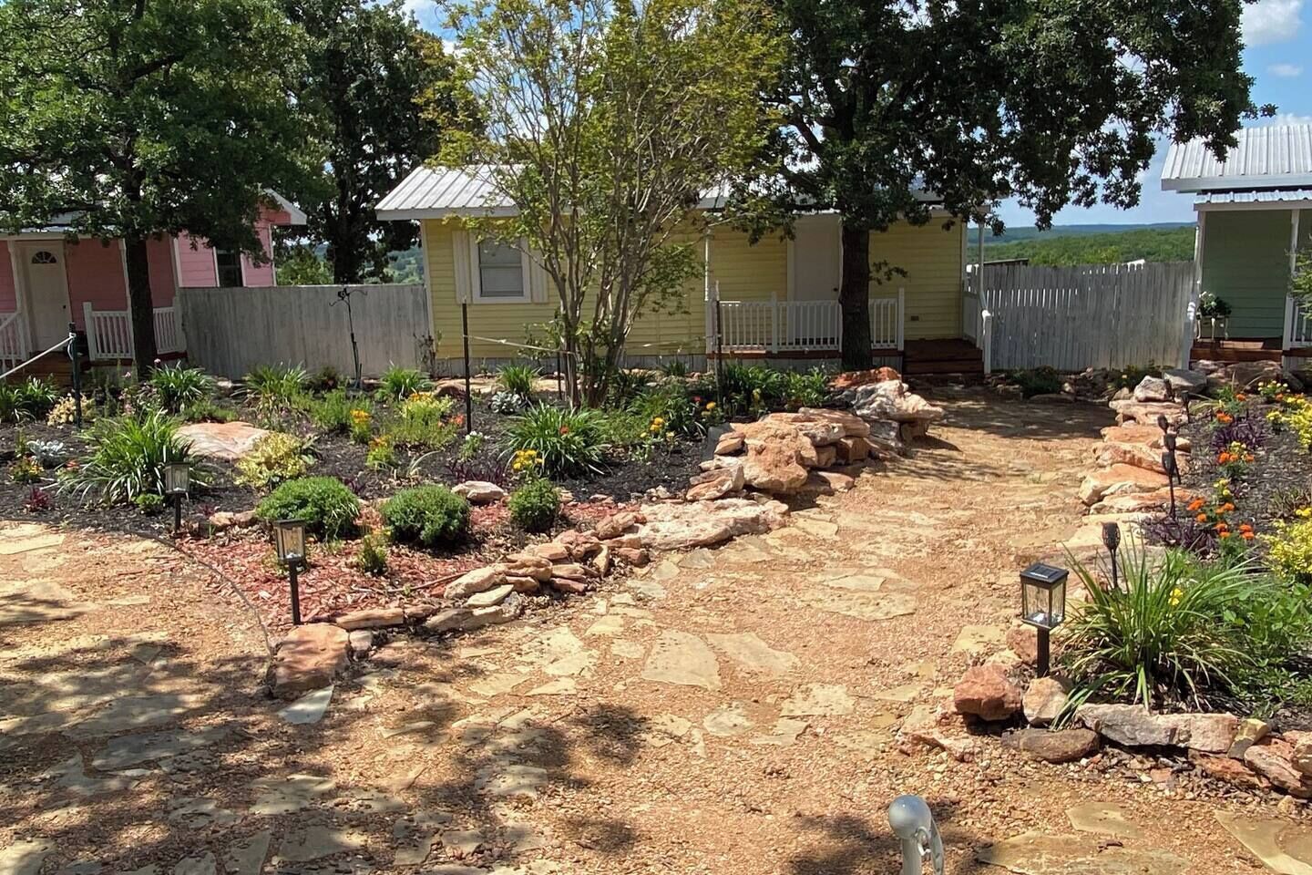 A garden with a variety of plants and a stone pathway.