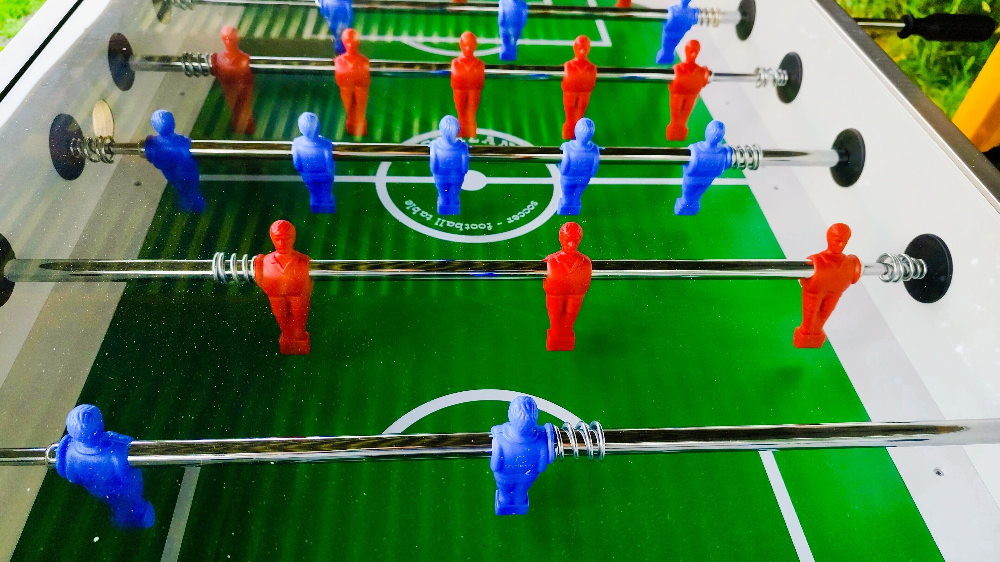 Ein Tischfußballtisch mit roten und blauen Spielfiguren.