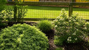 A yellow building with a stone wall and a fenced yard.