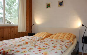 A double bed with floral bedding, a wooden headboard, and two bedside lamps.