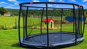 A trampoline with a safety net enclosure in a grassy area.