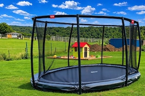 A trampoline with a safety net enclosure in a grassy area.