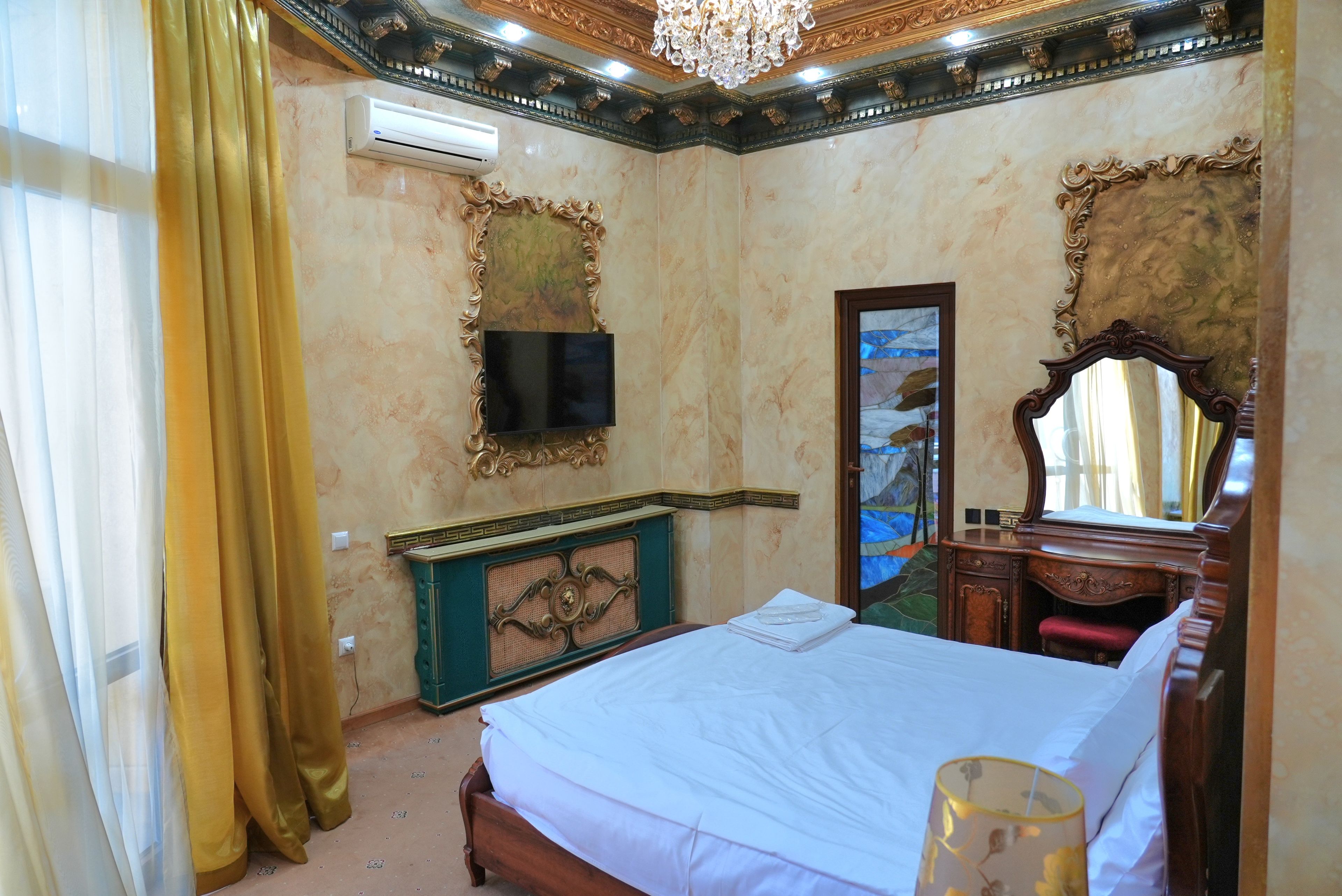Quarto de hotel com cama, televisão, espelho e um aparador decorativo.