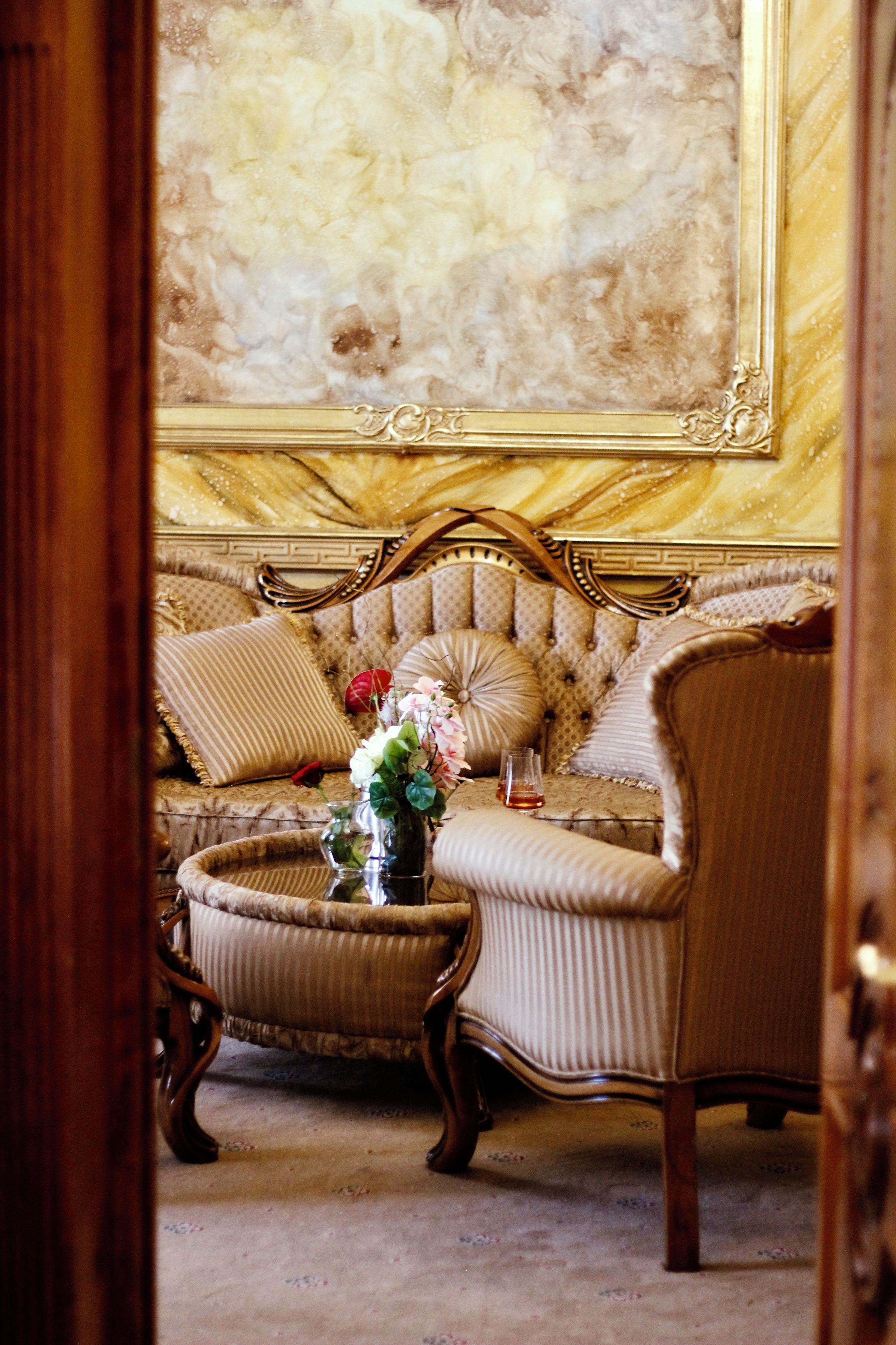 Une pièce comprenant un canapé, des fauteuils, une petite table ornée d’un vase de fleurs et une grande œuvre d’art encadrée accrochée au mur.