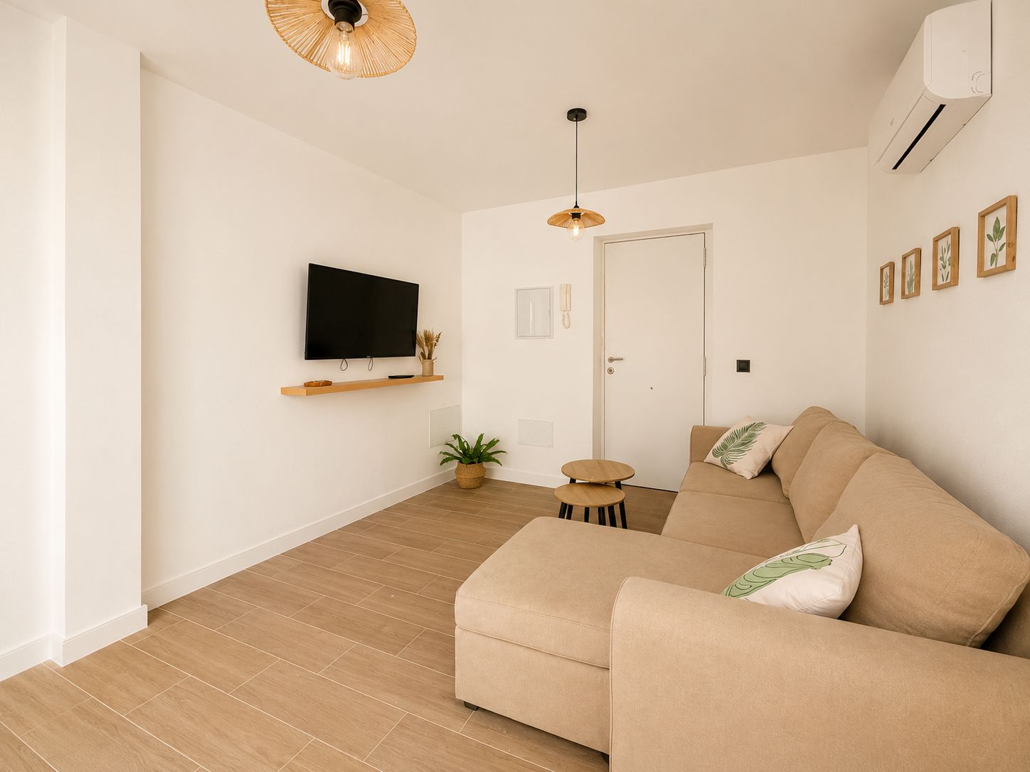 Una sala de estar moderna con un sofá, una televisión, una mesita y una planta en maceta.
