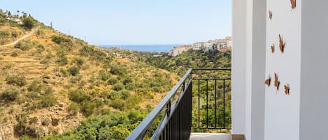 Un balcón con vista a un paisaje montañoso y el mar.
