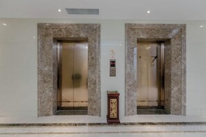 Two elevator doors with a control panel and a decorative object between them.