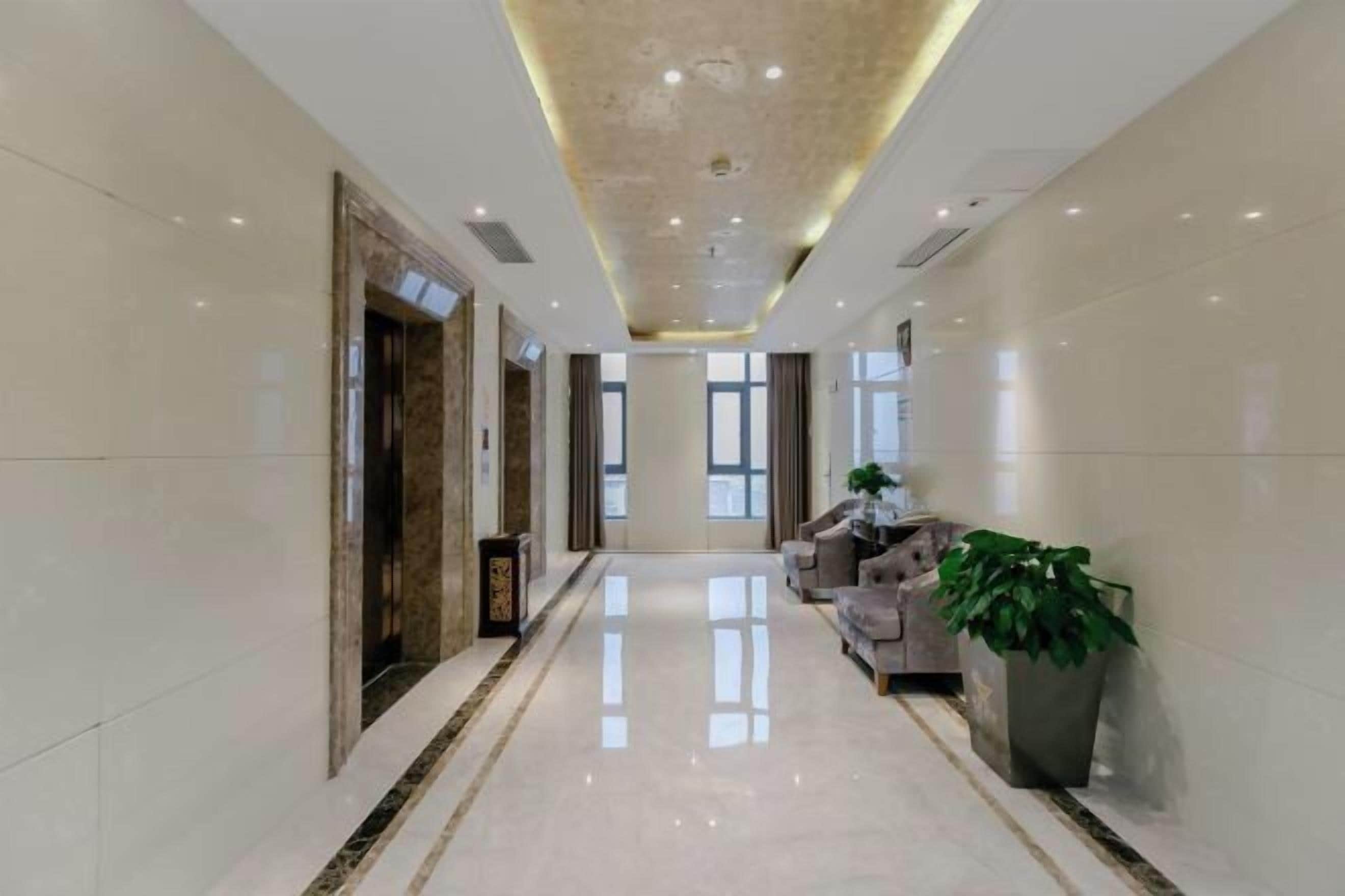 A hotel lobby with a long corridor, seating area, and a reception desk.