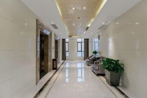 A hotel lobby with a long corridor, seating area, and a reception desk. - Xiushan Yaxi Hotel (Xiushan Railway Station) (Xiushan County)
