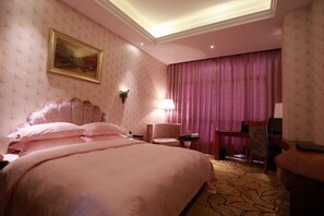 Una habitació d'hotel amb un llit gran, un escriptori, una cadira i un quadre a la paret.