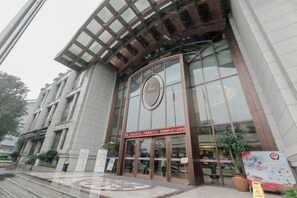 A building with a large glass entrance, a circular logo above the doors, and a sign with Chinese characters.