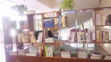 A library with multiple shelves filled with books, a potted plant on the top shelf, and a glass display case at the front.