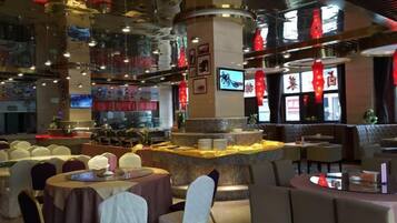 A restaurant with round tables, a central bar area, and a high ceiling with hanging lights.