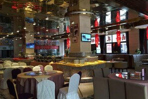 A restaurant with round tables, a central bar area, and a high ceiling with hanging lights. - Xiushan Yaxi Hotel (Xiushan Railway Station) (Xiushan County)