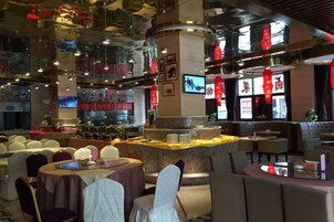 Um restaurante com mesas redondas, um balcão central e um teto alto com luminárias pendentes.