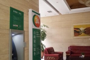 A reception area with a green sign, a 24-hour service sign, a red sofa, and a painting on the wall. - Xiushan Yaxi Hotel (Xiushan Railway Station) (Xiushan County)