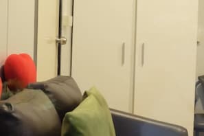 Une pièce avec une chaise bleue, une armoire blanche et une porte.