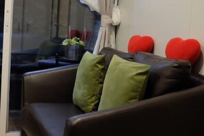 A brown leather sofa with green and red heart-shaped pillows. - KORA-GREAT Phuket Airport (Phuket)