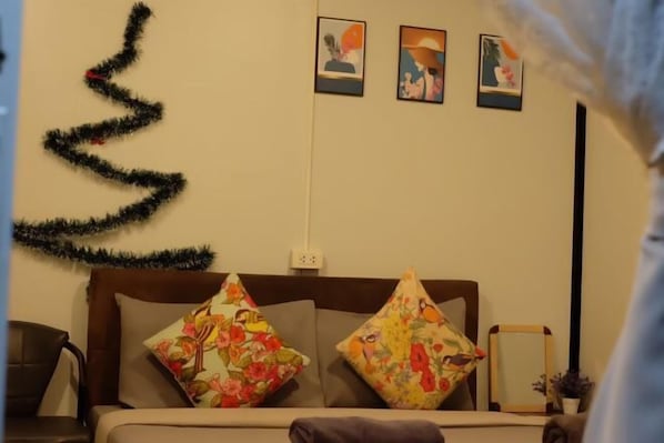Une chambre à coucher avec un lit, deux oreillers, un sapin de Noël fixé au mur et trois tableaux encadrés.