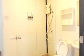 A bathroom with a toilet, a sink, and a shower. There are soap dispensers and a towel rack. - KORA-GREAT Phuket Airport (Phuket)
