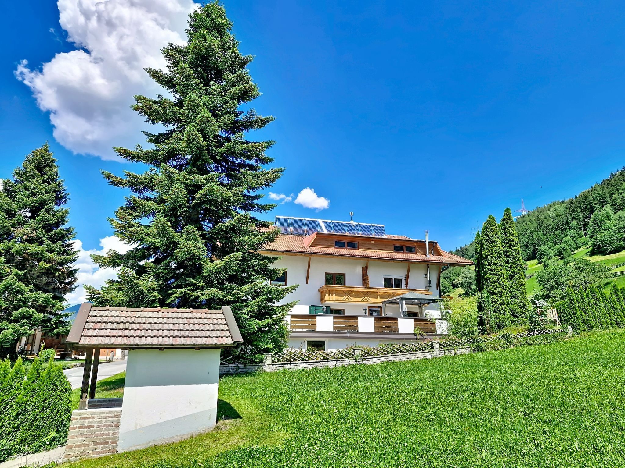 Ein zweistöckiges Haus mit geneigtem Dach, Solaranlage und einem kleinen Anbau mit Ziegeldach.