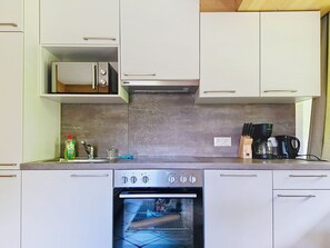 A compact kitchen with a built-in oven, a microwave, and a coffee maker. - Apart Nachtigall by Interhome (Arzl im Pitztal)