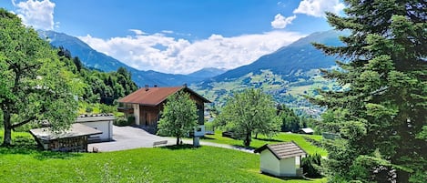 A rural landscape with a house, a small shed, and a picnic area.