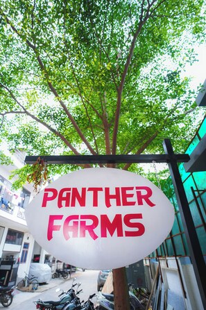 A sign for 'Panther Farms' hanging from a tree.